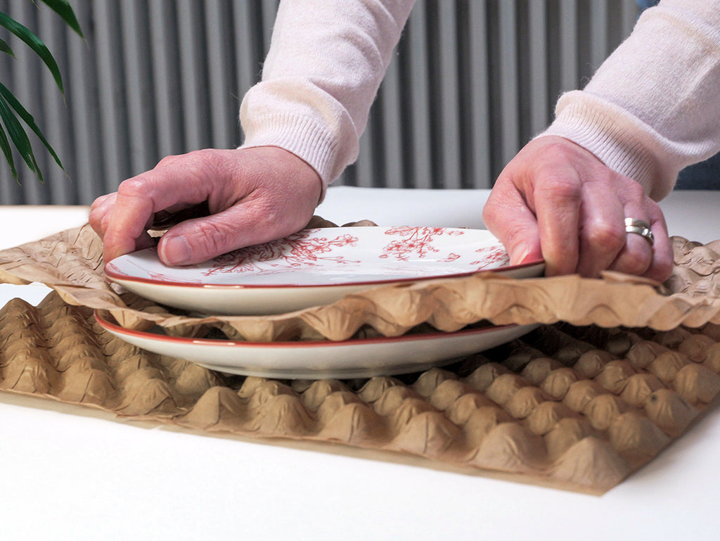 Une personne utilisant le produit Naturbubble afin de protéger des assiettes