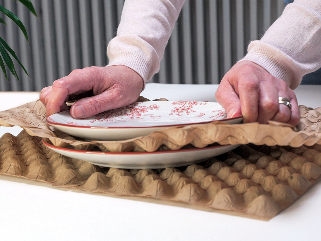Une personne utilisant le produit Naturbubble afin de protéger des assiettes