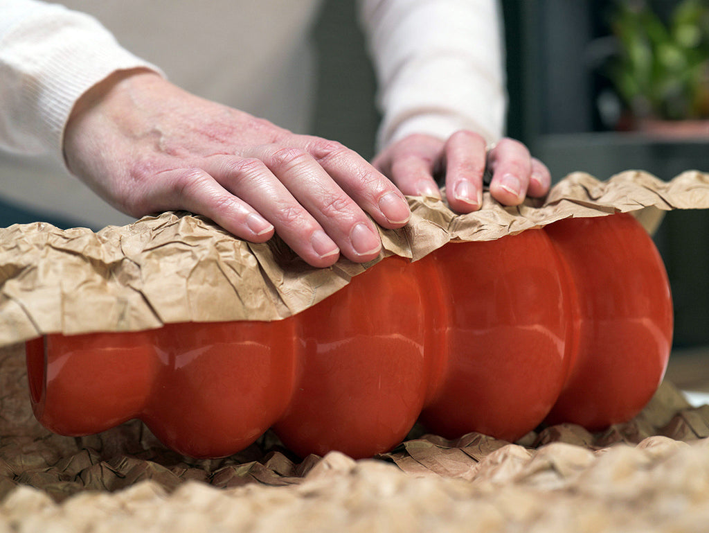 Une personne qui protège son vase grâce à Naturbubble le vrai papier bulle en l'enroulant.